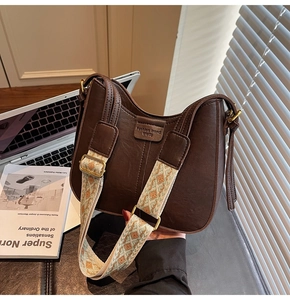 Detail of vintage brown bucket bag with geometric jacquard strap and leather texture