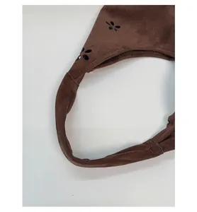 Detail of brown suede tote bag featuring laser-cut floral patterns and stitching