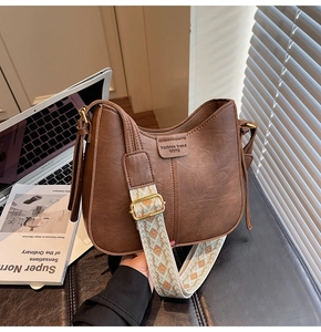 Detail of retro brown half-moon crossbody bag with ethnic wide woven shoulder strap