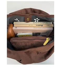 Macro view of brown suede tote bag interior showing large capacity and petal cut-outs
