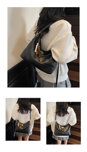 Detail of black quilted leather shoulder bag with gold turn-lock and wooden bead charm