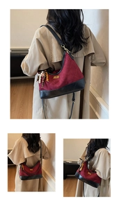 Detail of burgundy suede shoulder bag with black quilted leather and wooden bead charm