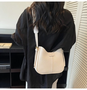 Detail of off-white PU leather bucket bag with printed wide strap on model back view