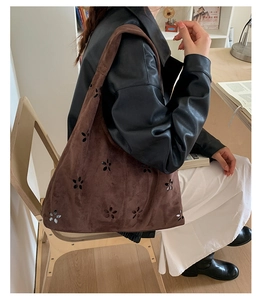 Brown suede tote bag with laser-cut floral patterns shown in a cozy lifestyle setting