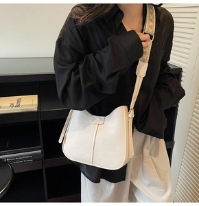 Detailed close-up of a white bucket bag with natural pleat texture and jacquard strap