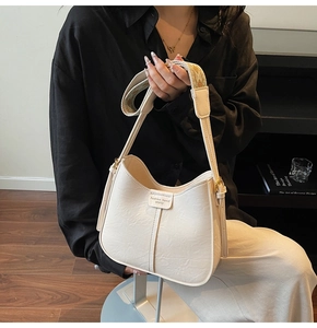 Close-up of beige pleated bucket bag with wide jacquard strap and textured finish