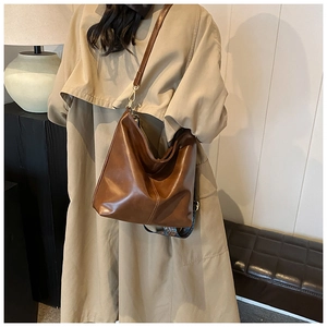 Détail du sac hobo en cuir huilé marron avec une large bandoulière à motif vintage