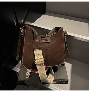 Detail of vintage brown leather bucket bag with geometric patterned wide strap on stairs