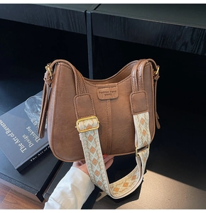 Close-up of retro brown bucket bag with wide geometric embroidered shoulder strap