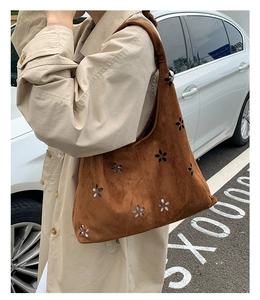 Close-up of brown suede tote bag with laser-cut floral patterns and metal hardware details