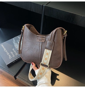 Detail of vintage brown Hobo bag featuring a patterned wide strap and embossed texture