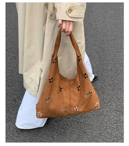 Street style shot of a brown laser-cut flower tote bag in suede texture with beige trench coat