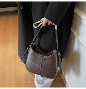 Detail of vintage dark brown bucket bag with textured leather and Fashion trend logo