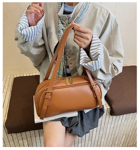 Détail macro du sac cylindrique en cuir marron avec dorures et double fermeture éclair