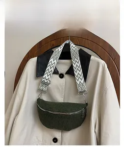 Detailed close-up of green corduroy waist bag with geometric patterned shoulder strap