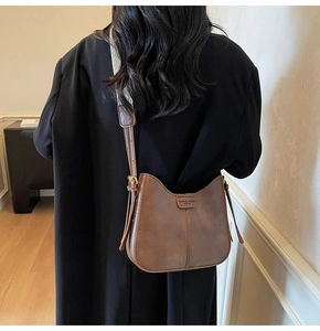 Detail of retro brown crescent bag with ethnic pattern wide strap and logo tag