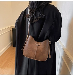 Close-up of brown vintage bucket bag with Fashion trend YWVTU logo on long strap