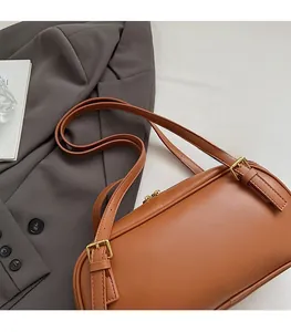 Détails des bretelles réglables en cuir et boucles dorées sur un sac baguette marron