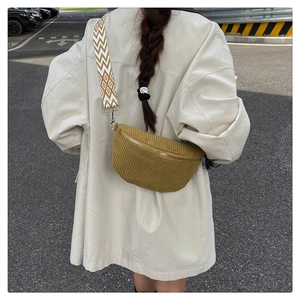 Close-up of yellow corduroy belt bag with vintage geometric strap on beige coat