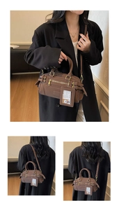 Detail view of retro brown Boston bag with matte leather texture and metallic hardware