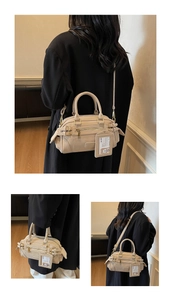 Detail view of beige boston bag showing dual handles, adjustable strap and card holder pendant