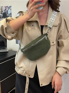 Dark green corduroy waist bag with geometric woven strap worn as a crossbody chest pack