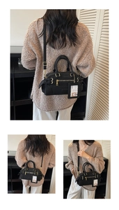 Detail of black Boston bag with gold hardware, detachable strap, and hanging card slot