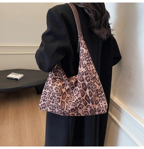 Close-up of large leopard print tote bag with leather strap worn by a female model