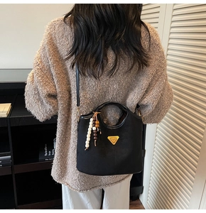 Dettaglio borsa a secchiello in camoscio nero con perline colorate e logo a triangolo oro