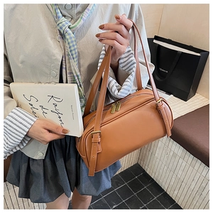 Détail du sac Boston marron chaud avec boucles en métal et fermetures éclair dorées