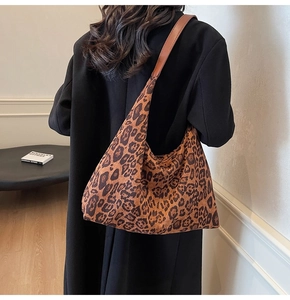 Detail of stylish leopard print tote bag with brown leather strap worn over a black coat