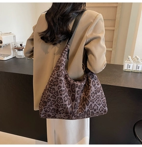 Detail of a large leopard print tote bag with a black leather shoulder strap and soft fabric