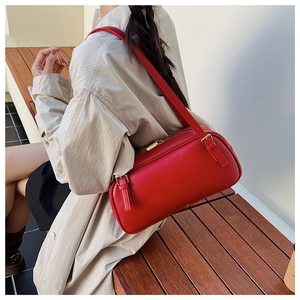 Détail du sac sous le bras en cuir rouge avec zip doré dans un cadre de vie extérieur