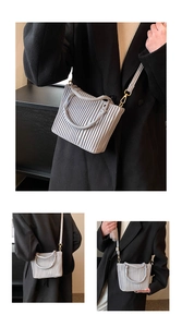 Detail of light grey striped pleated bucket bag with polished gold hardware and strap
