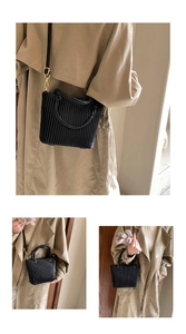 Detail of black pleated bucket bag featuring elegant gold hardware and a sleek handle