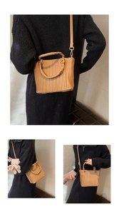 Detail of a brown pleated bucket bag showing vertical accordion folds and adjustable strap