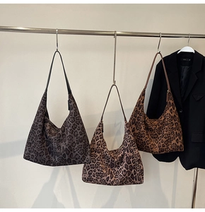 Three leopard print hobo bags in grey, khaki, and brown hanging on a metal display rack