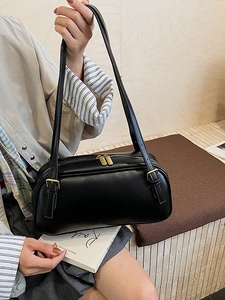 Sac à épaule minimaliste en similicuir noir avec fermetures éclair dorées porté par mannequin
