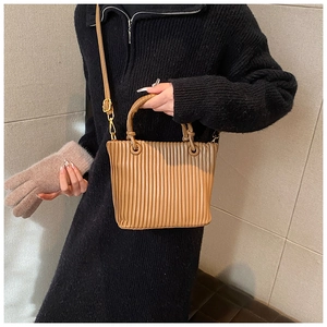 Detail shot of caramel pleated bucket bag texture with gold hardware and shoulder strap