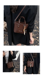 Detailansicht der braunen Webstruktur-Tasche mit Holzperlen und Metall-Logo-Schild