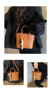 Detailansicht einer stilvollen braunen Flecht-Handtasche mit Perlen-Quaste