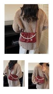 Détail du sac rouge plissé brillant avec poignée en perles et bandoulière en cuir
