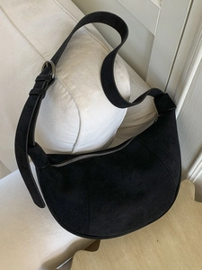 Matte black suede crescent hobo bag with adjustable wide shoulder strap and metal buckle
