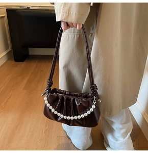 Détail du sac plissé en cuir verni marron foncé avec élégante chaîne en perles