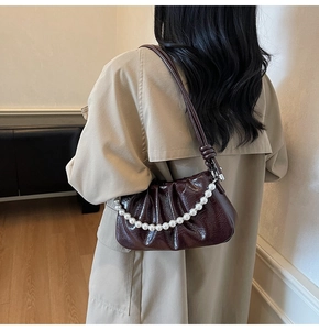 Détail d'un sac à bandoulière froncé bordeaux en cuir verni avec chaîne de perles