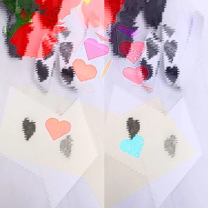 Macro detail of holographic heart stickers with glitter finish on a white envelope