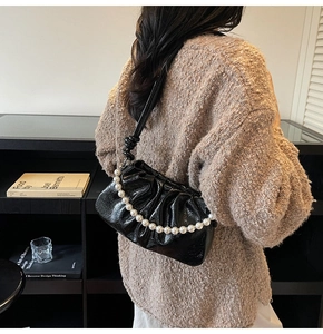 Détail du sac nuage noir plissé avec une élégante poignée en perles blanches chic