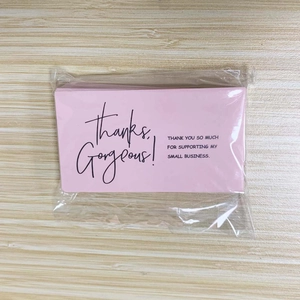 Macro shot of pink Business Thank You cards stacked on a light wood background