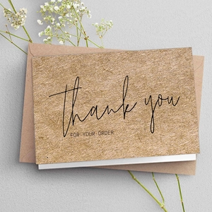 Kraft thank you cards and envelopes set on grey background with decorative flowers