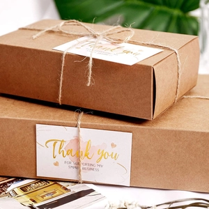 Close-up of Thank You stickers on kraft gift boxes with natural twine and floral accents